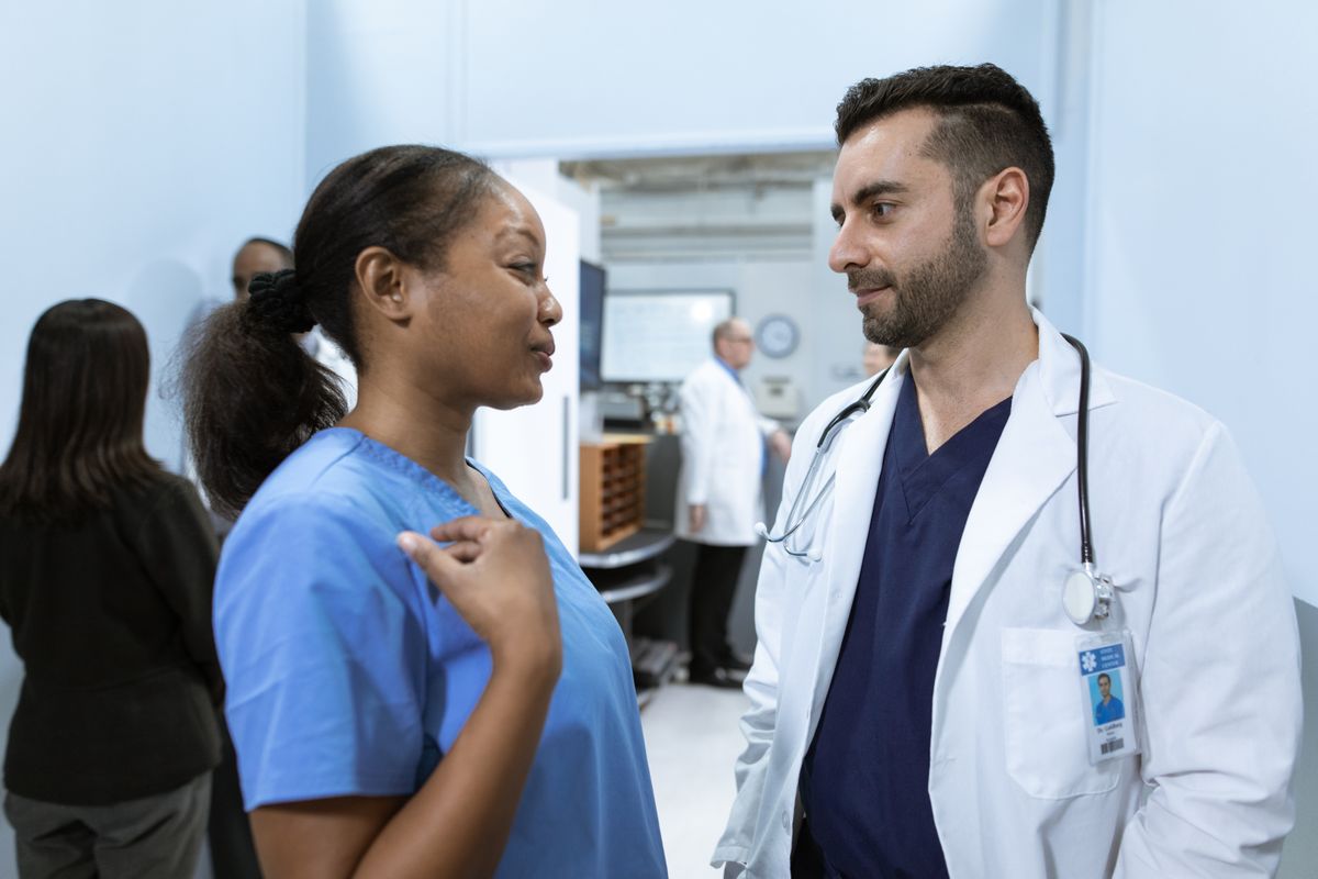 Two clinicians conferring in a hospital corridor